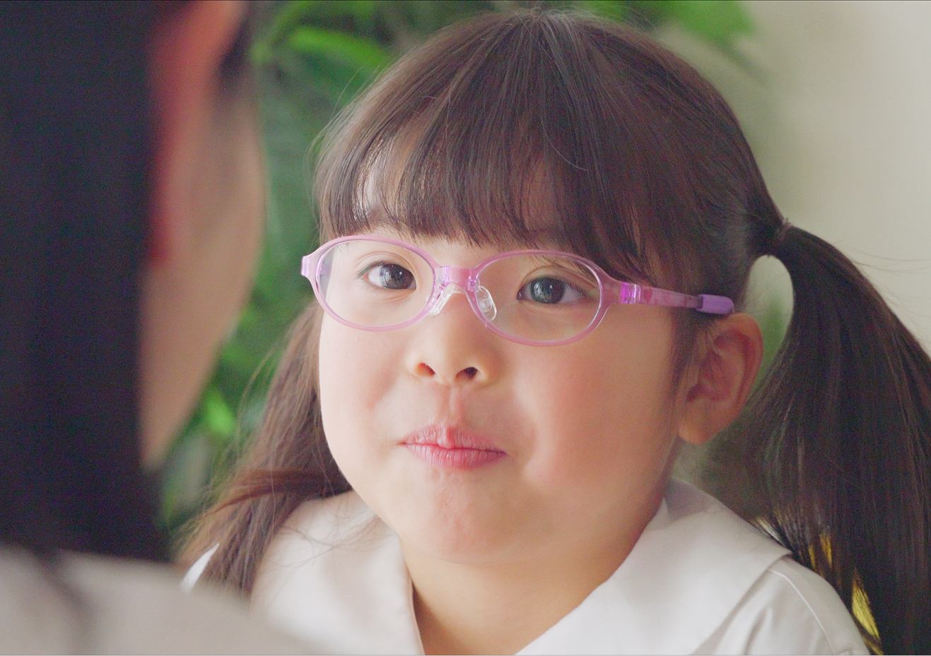 安全で軽量なトマトグラッシーズのピンクの治療用メガネを着用して、笑顔を見せる女の子の写真。
